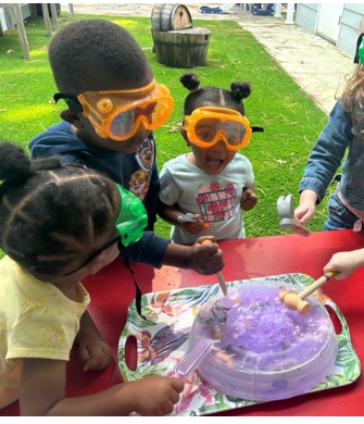 KALE children wearing safety goggles and exploring a colorful hands-on science activity outdoors